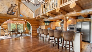 L’intérieur d’une cabane en rondins comprend un coin repas, une cuisine et un balcon décoré d’une tête de cerf.