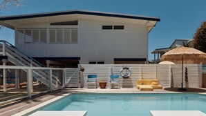Una casa moderna con piscina, un porche cubierto y una escalera que conduce a un nivel superior.
