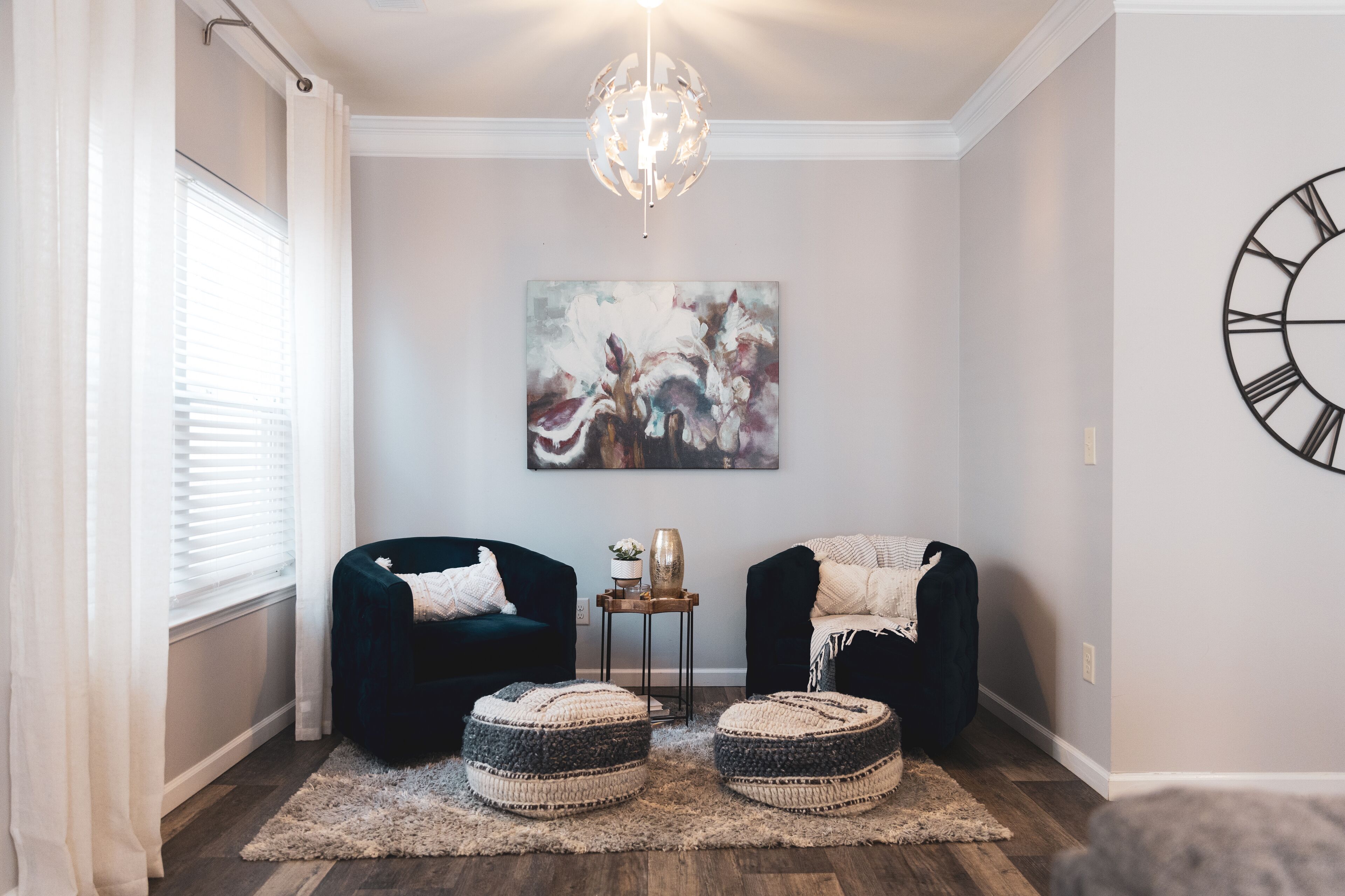 Un salon chaleureux avec deux fauteuils confortables aux couleurs sombres, une table basse ronde et un tableau décoratif accroché au mur.