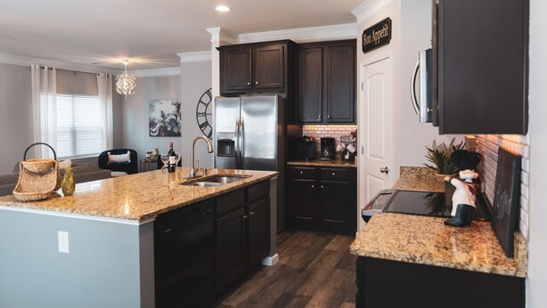 A modern kitchen with dark cabinetry, granite countertops, and stainless steel appliances.