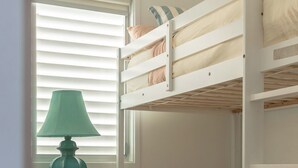 A bunk bed room with a desk and a lamp.