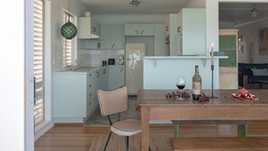 A modern kitchen with light blue cabinets, a wooden dining table, and a potted plant.