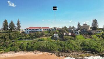 A coastal hotel with a prominent flagpole, beachfront property, and surrounding greenery.