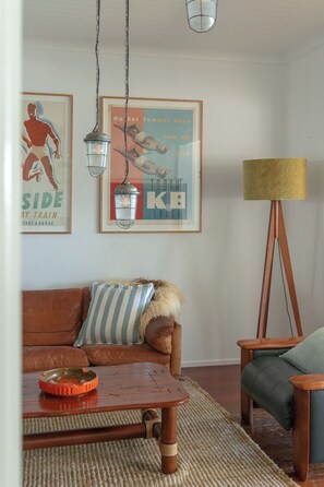 Un salon avec un canapé en cuir marron, une table basse en bois, un coussin à rayures et un lampadaire.