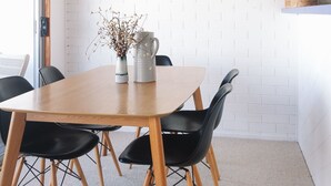 A dining area with a wooden table, black chairs, and a hanging light fixture. - BAY PROPERTIES | The Loft Yamba (Yamba)