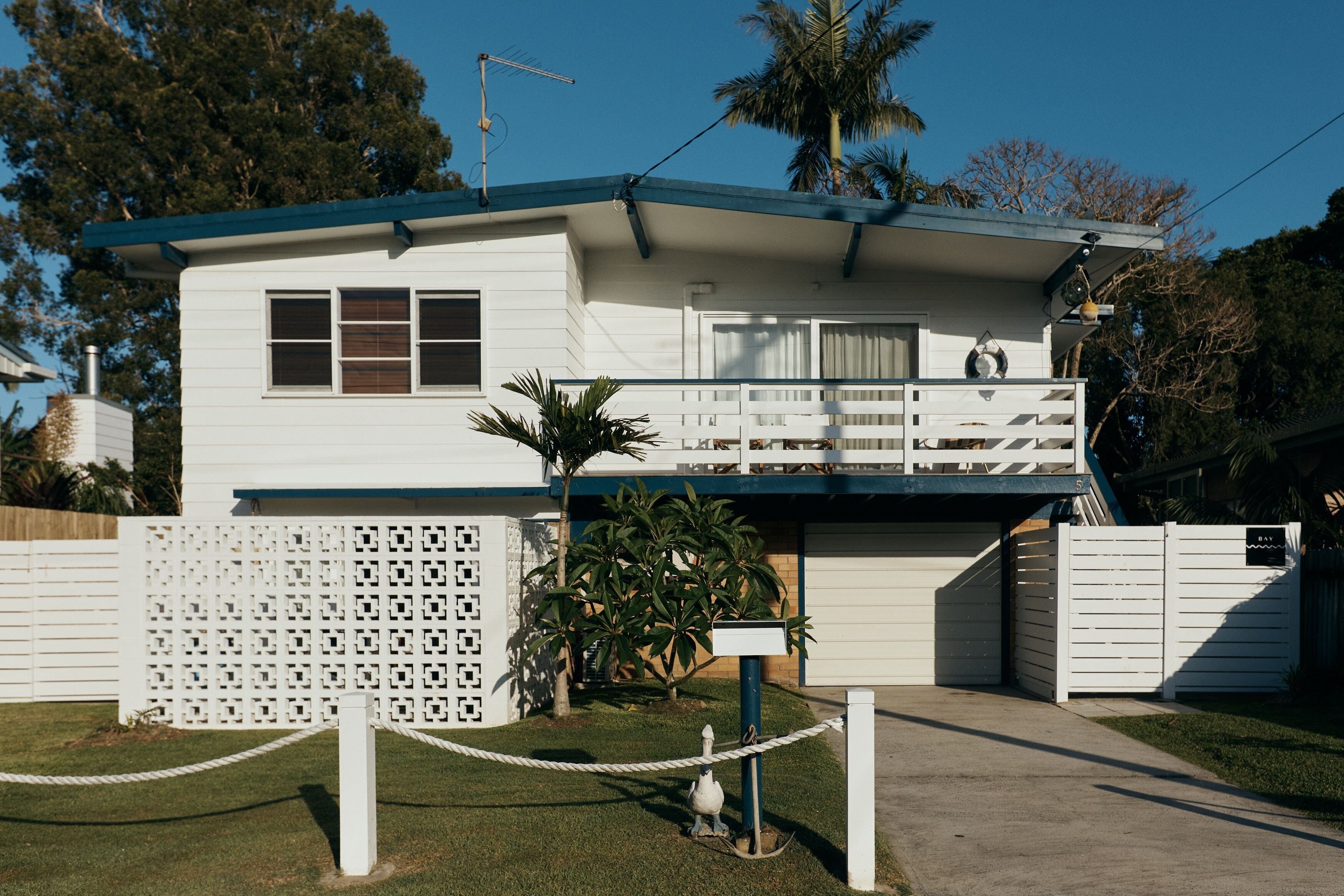 A single-story house with a balcony, a garage, and a fenced yard.
