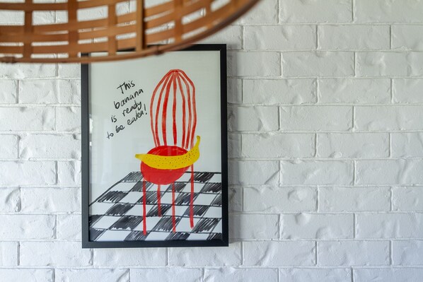 A framed artwork on a white brick wall.
