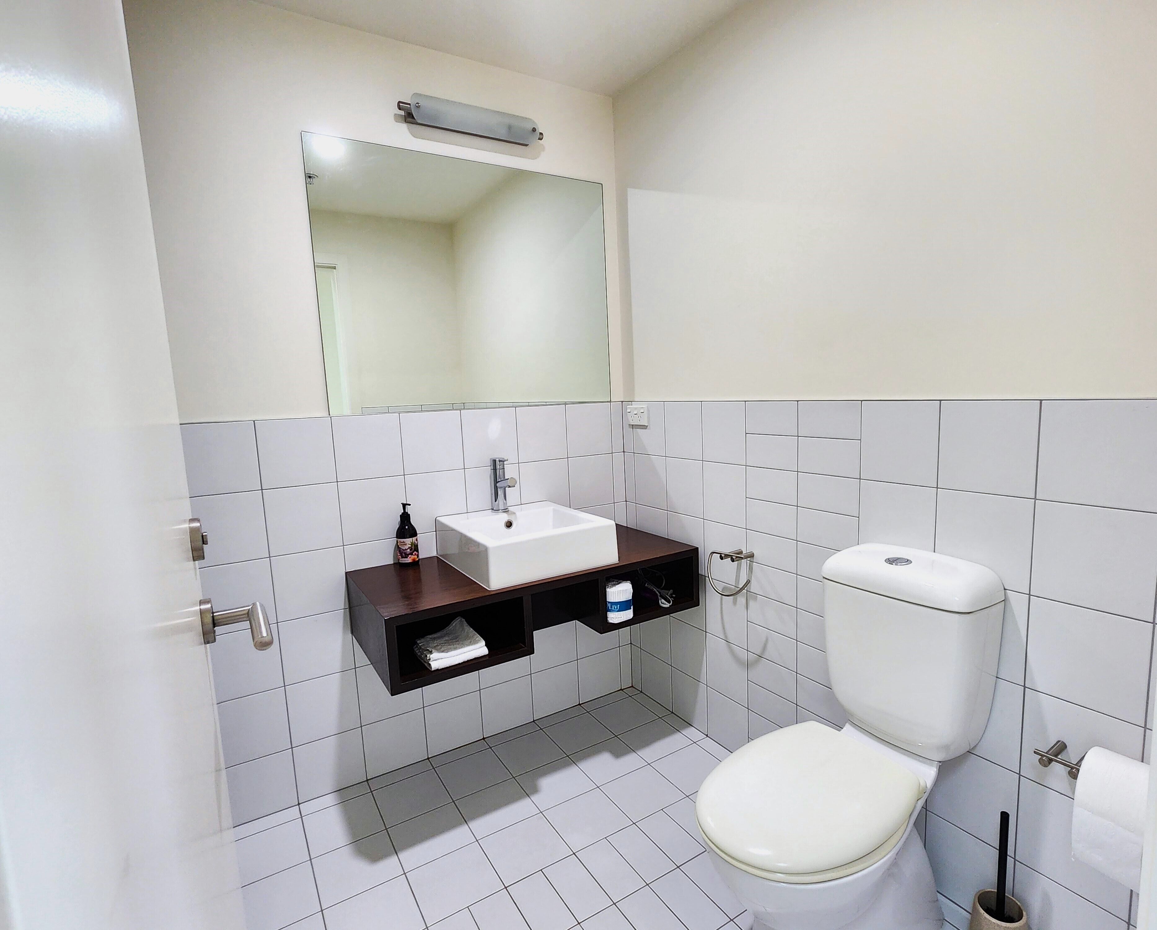 Un baño con lavamanos, espejo y retrete.