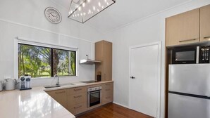Une cuisine moderne dotée d’un plan de travail en bois, d’appareils électroménagers en acier inoxydable et d’une grande fenêtre offrant une vue sur la verdure.