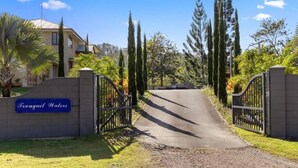 Une entrée fermée par un portail donne accès à une propriété résidentielle appelée « Tranquil Waters », et une allée pavée mène à la maison.