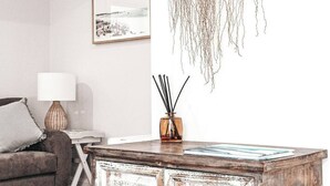 Un salon avec une table basse en bois, une lampe, un tableau encadré au mur et une plante suspendue.