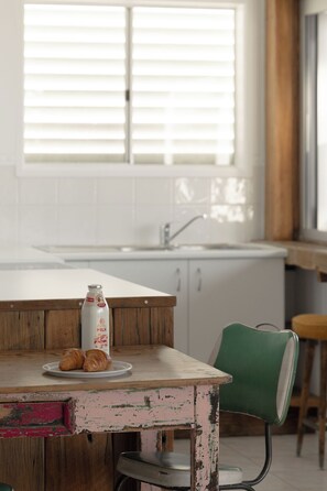 Een keuken met een houten tafel, een groene stoel en een fles melk.