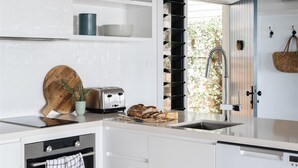 Eine moderne Küche mit weißen Schränken, einem Einbauofen, einem Toaster und einem Weinkühlschrank.