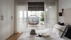 Ein Schlafzimmer mit Bett, Hängesessel, Kleiderschrank und Blick ins Freie.