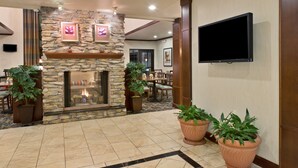 Un vestíbulo con chimenea de piedra, plantas en macetas, un televisor de pantalla plana y un comedor.