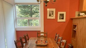 Una sala da pranzo con un tavolo in legno, sei sedie, un lampadario e due quadri appesi al muro.