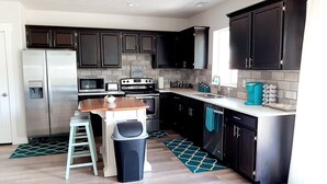 A modern kitchen with dark cabinets, stainless steel appliances, and a wooden table.