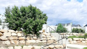 A stone retaining wall with a grassy area and a metal staircase.