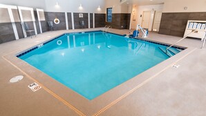 Una piscina interior con carriles claramente marcados, una silla de salvavidas y un área de vestuarios.