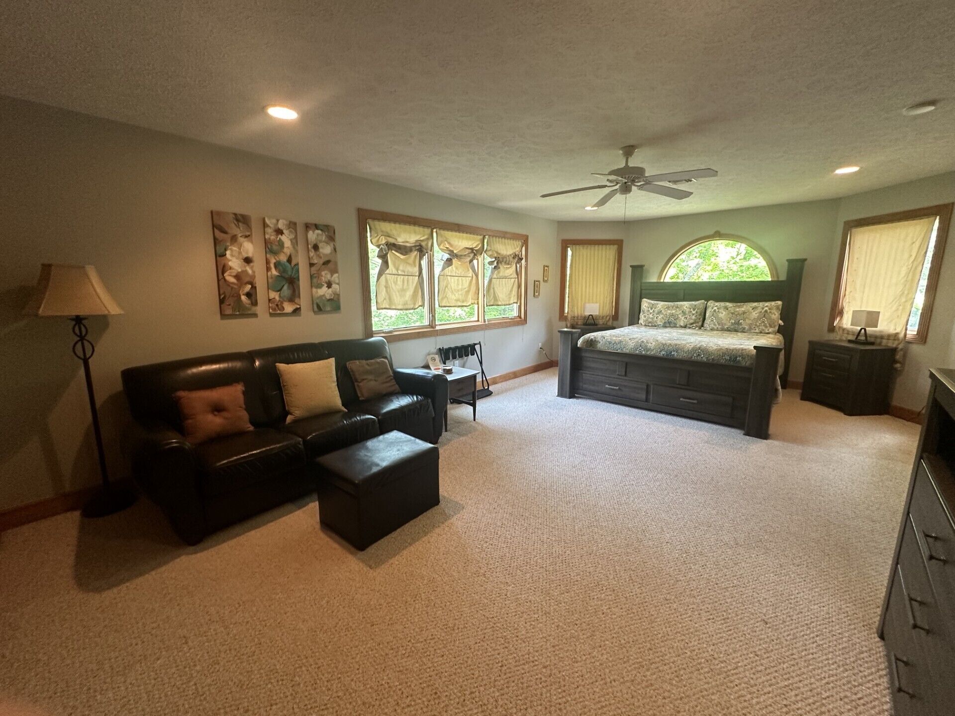 A bedroom with a bed, a sofa, a desk, and a chair.