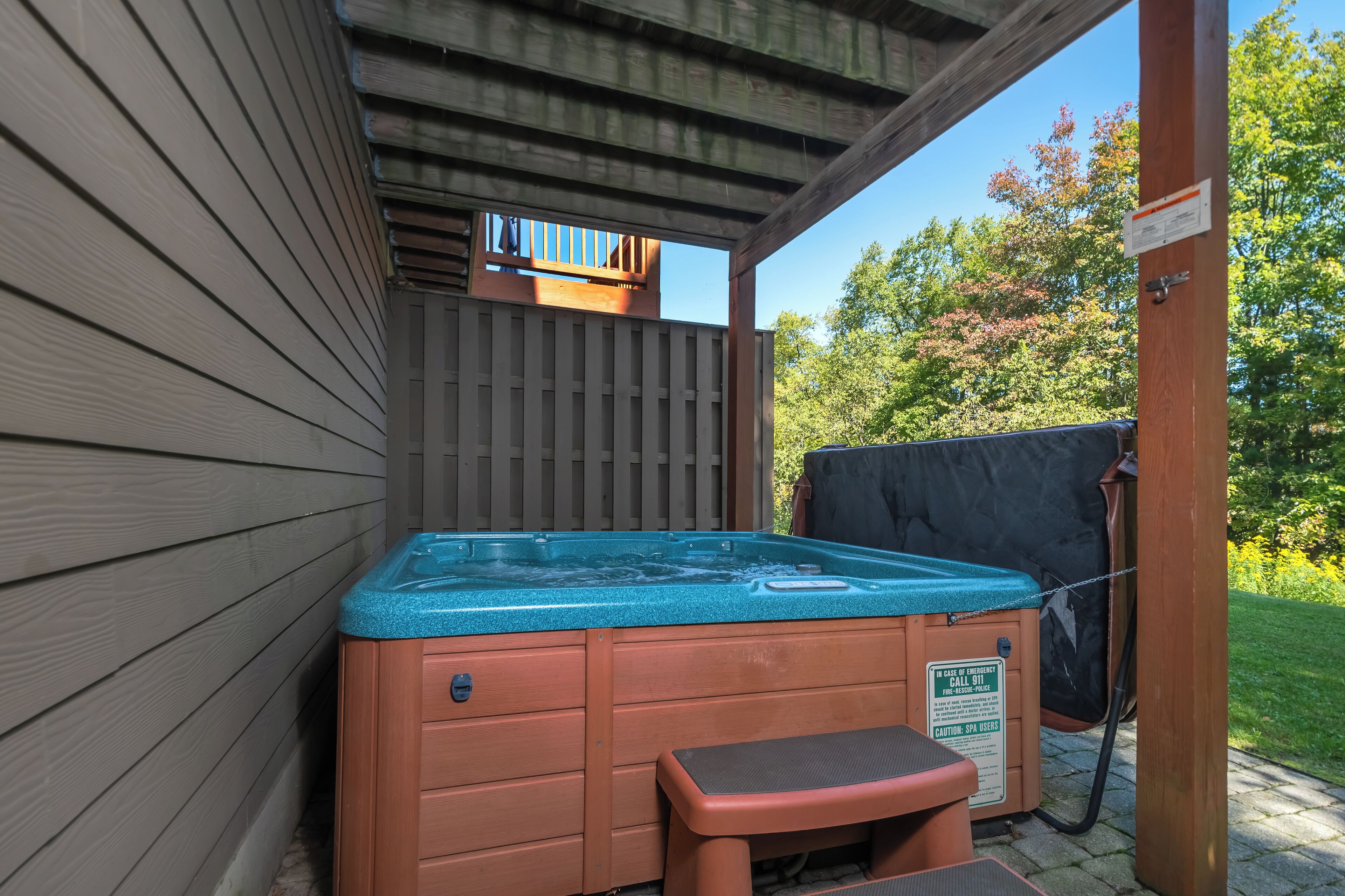 A hot tub with a wooden deck and a safety sign.