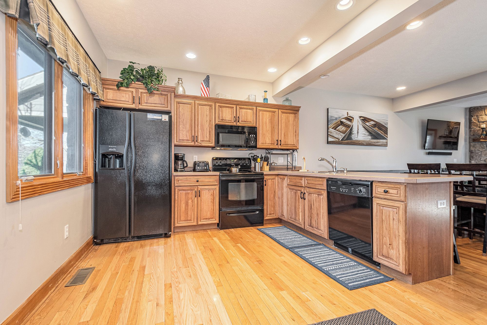 A modern kitchen with wooden cabinets, a refrigerator, stove, microwave, and dishwasher.