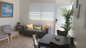 En stue med sofa, to stole, et bord og en potteplante.