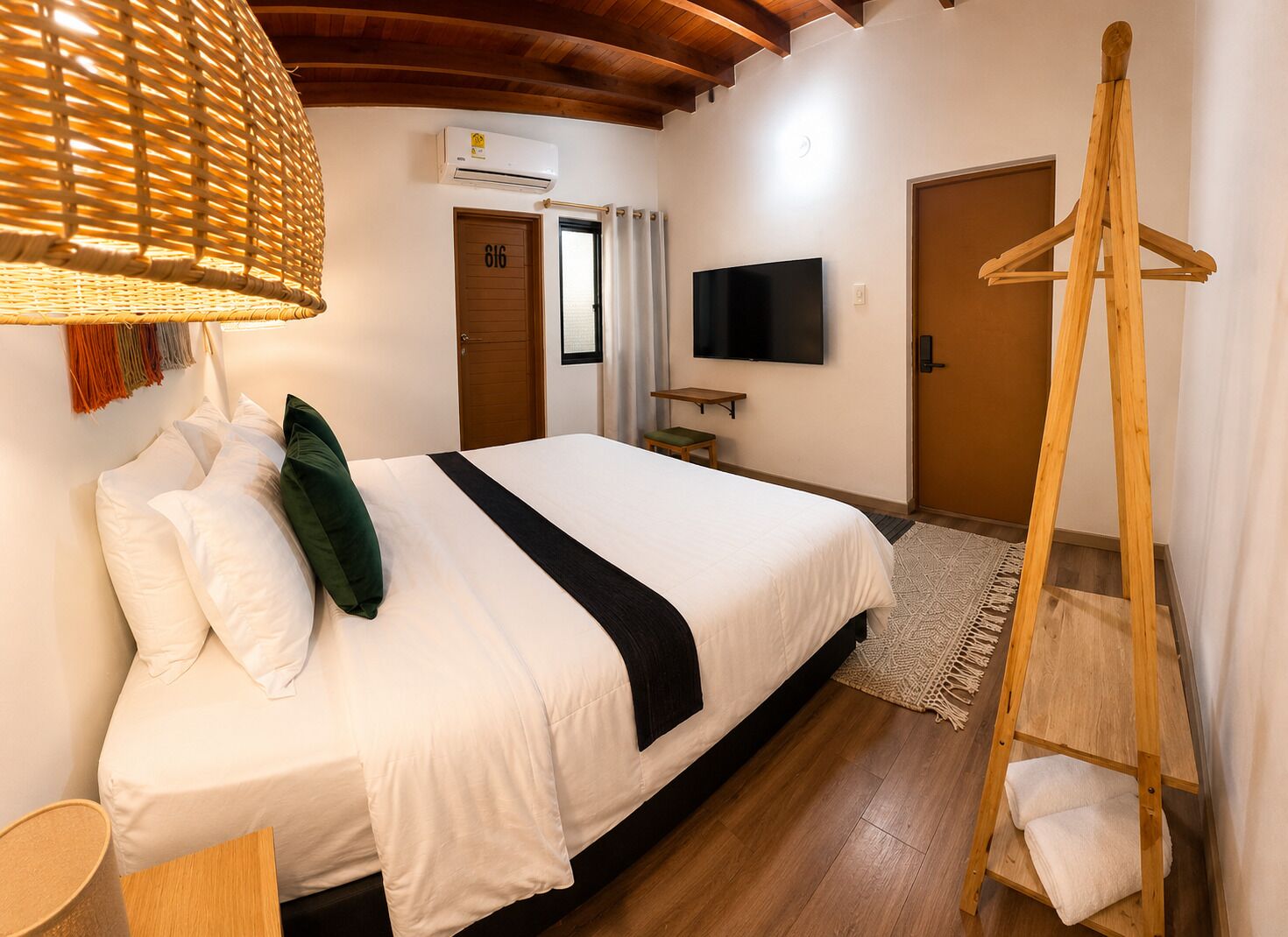 A hotel room with a bed, a television, a wooden ladder, and a door.