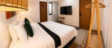 A hotel room with a bed, a television, a wooden ladder, and a door.