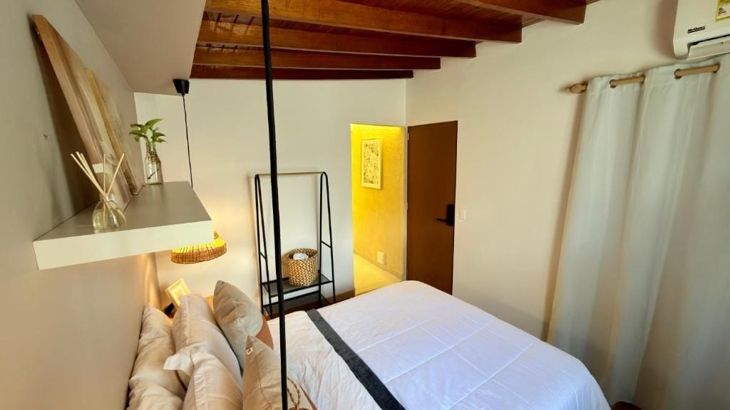 A bedroom with a bed, bedside table, lamp, and a shelf with decorative items.