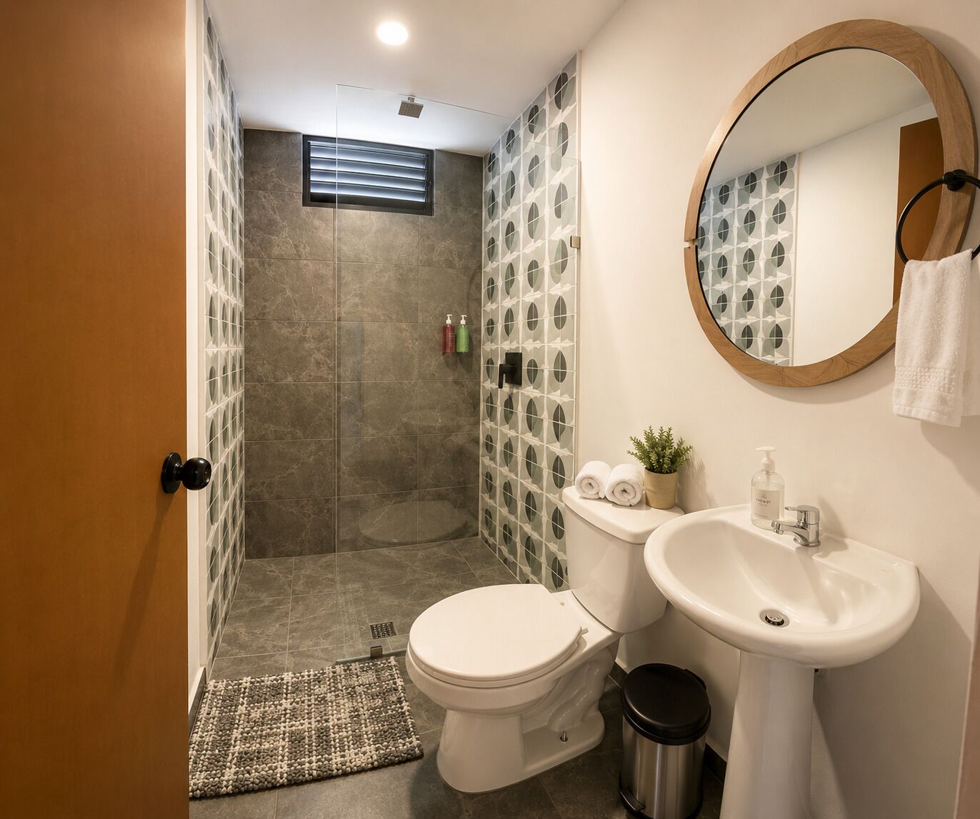 A bathroom with a shower, toilet, sink, and a mirror.