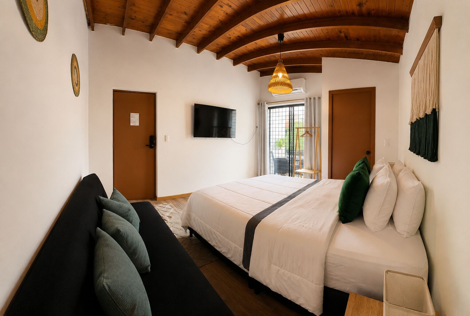 Une chambre à coucher avec un lit, un canapé, une télévision et un plafond en bois.