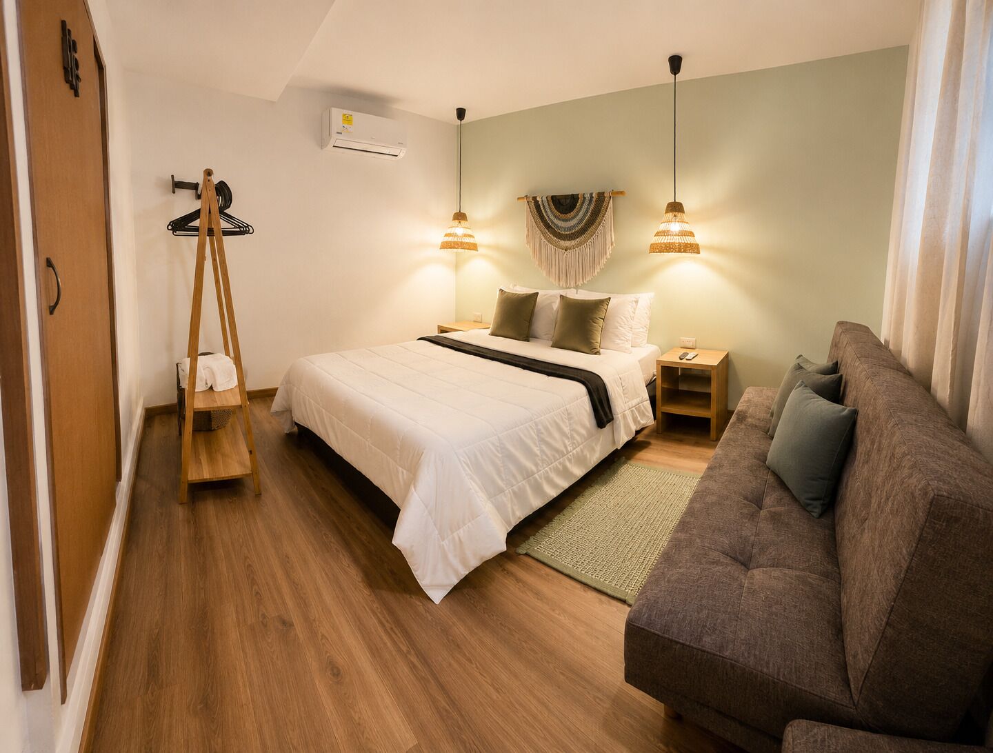 Ein Schlafzimmer mit einem Bett, Nachttischen, einer Pendelleuchte, einem Holzschrank und einem Sofa.