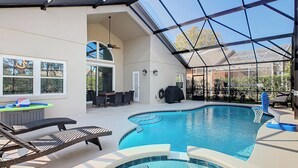 Un espace extérieur abrité avec une piscine, des chaises longues, une table à manger et un ventilateur de plafond.
