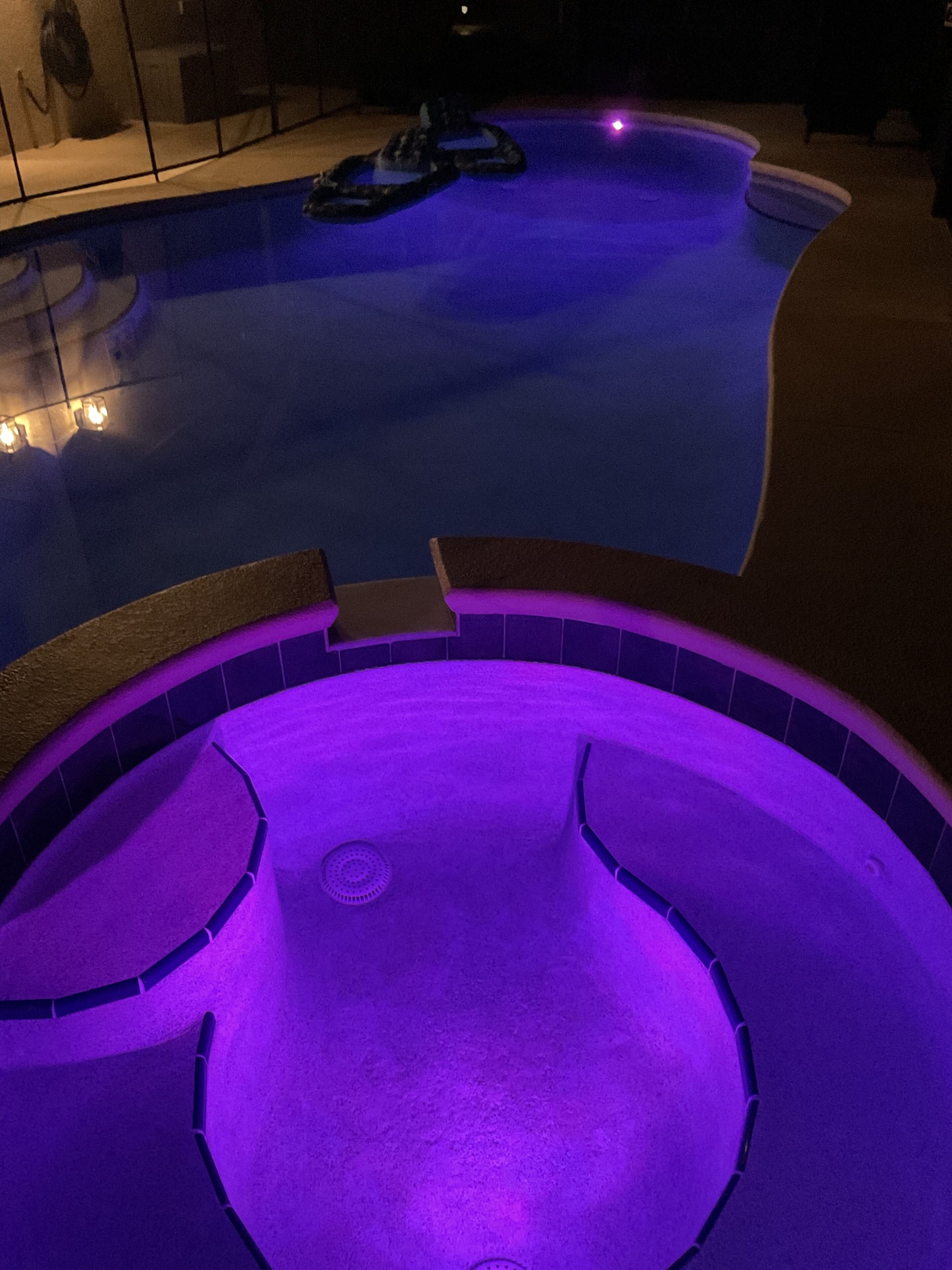 Een zwembad met een whirlpoolgedeelte, omgeven door een betegeld terras.