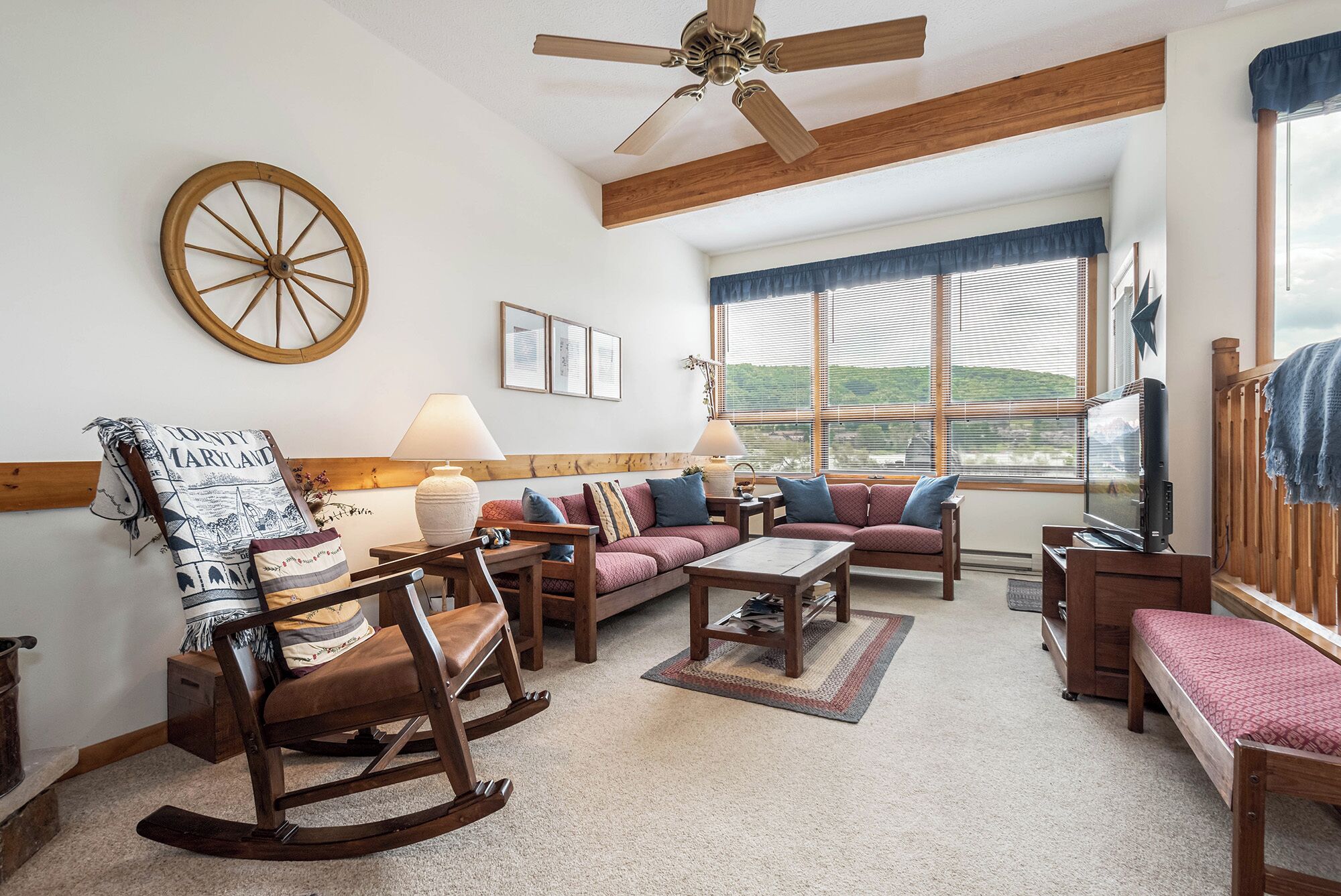 A cozy living room with a rocking chair, a sofa set, a wooden coffee table, and a television.