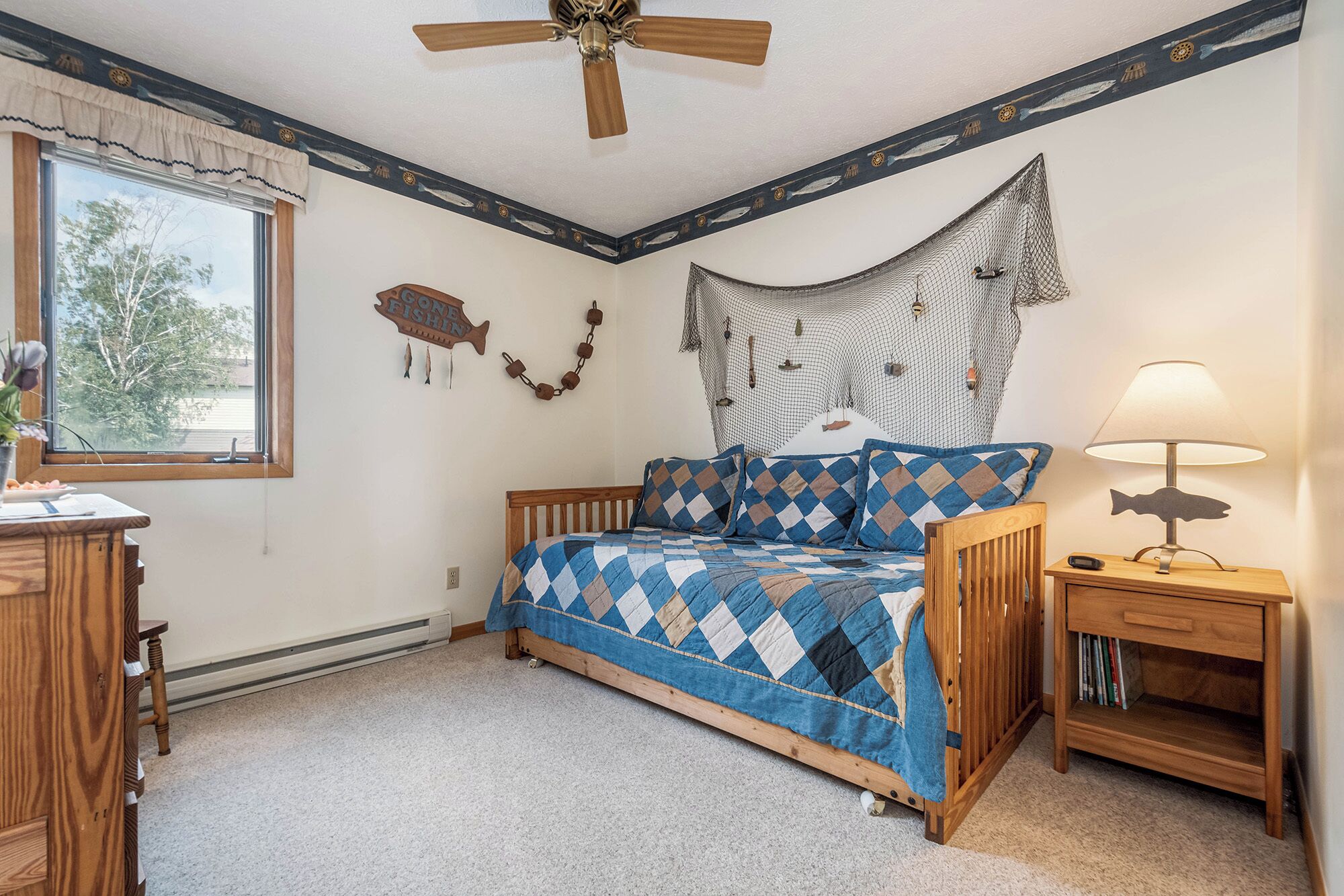 A bedroom with a bed, a nightstand, a lamp, a window, and a ceiling fan.