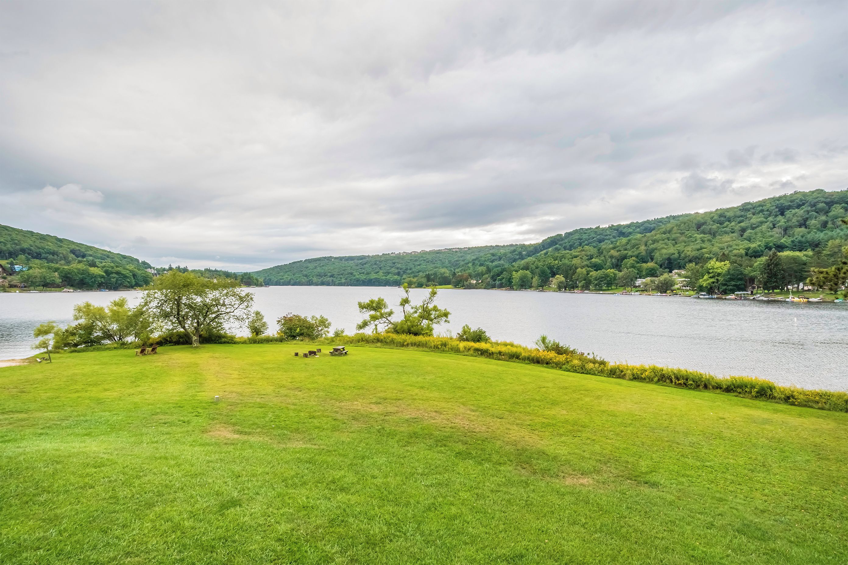 A grassy area with a lake and hills in the background.