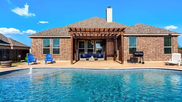 Une maison avec une piscine, un patio couvert et une façade en briques.