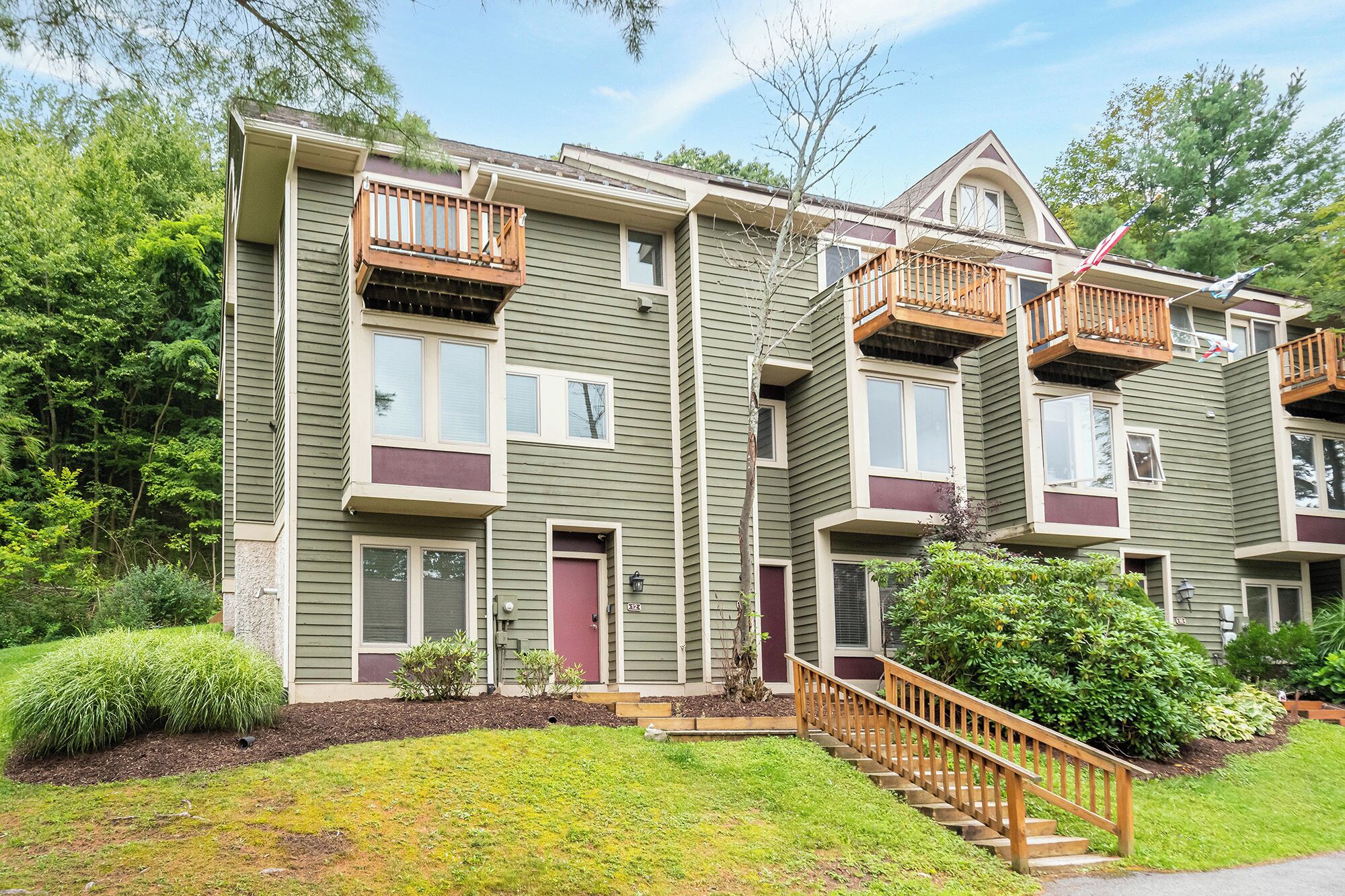 A multi-story residential building with a central entrance, a small porch, and a staircase leading to the upper floors.