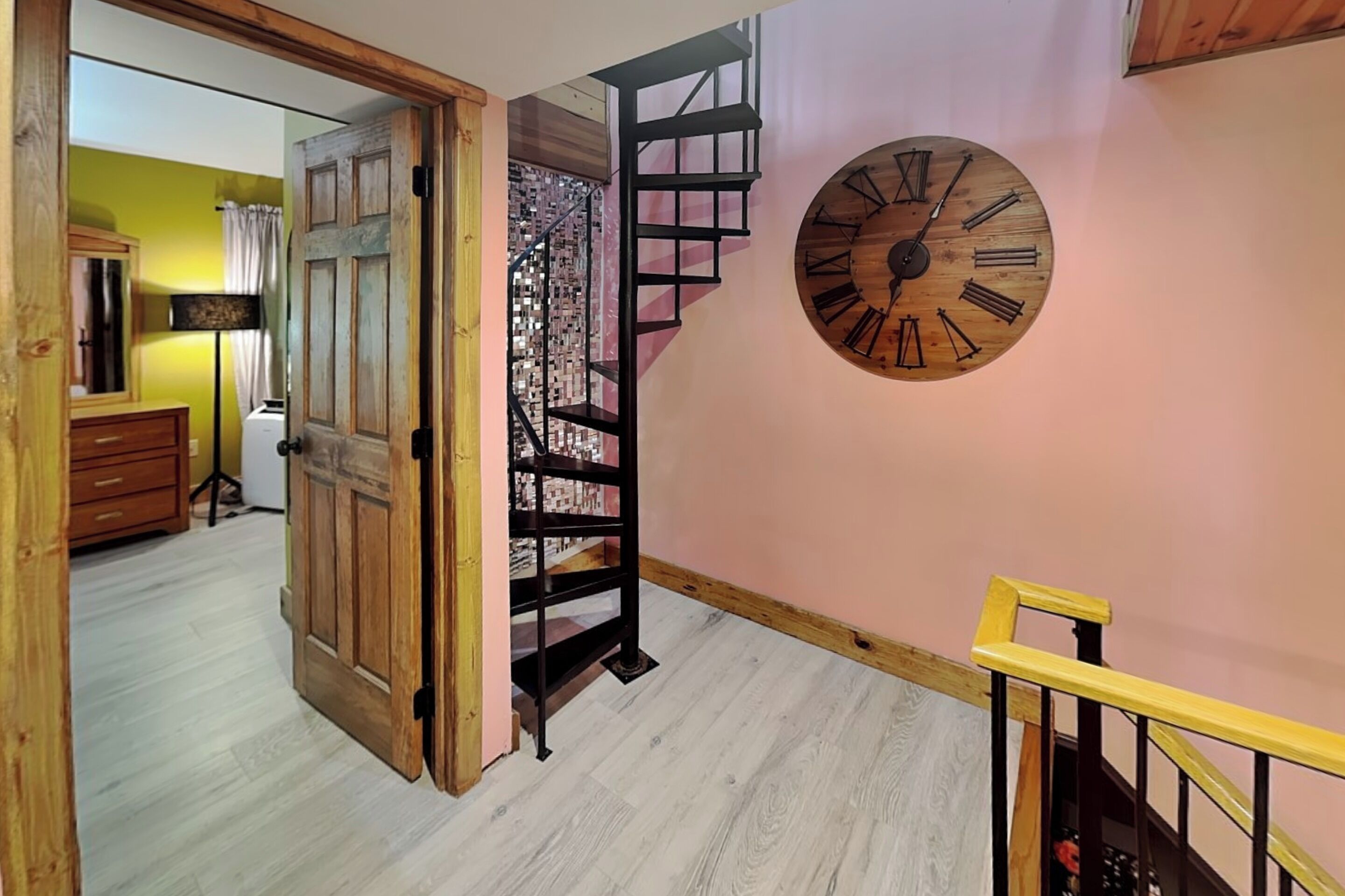 Un escalier avec une rampe en bois et une horloge murale.