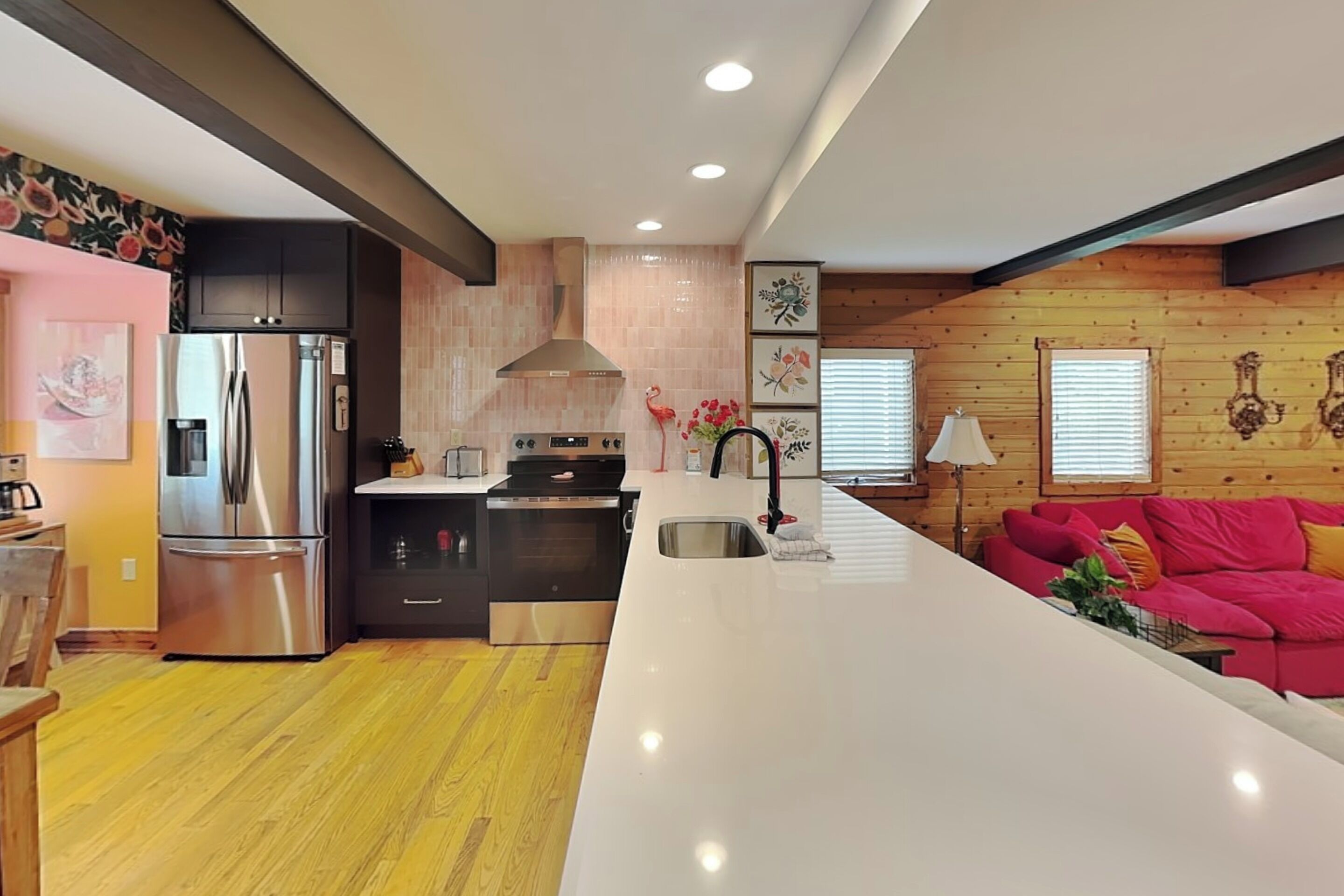 A modern kitchen with stainless steel appliances, a central island, and a wooden wall with artwork.