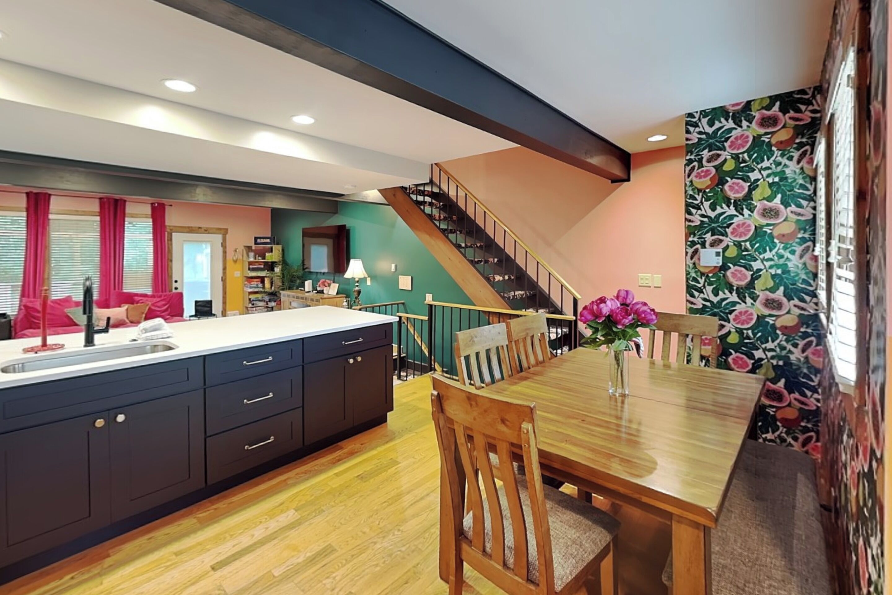 Une cuisine moderne dotée d’un îlot central, d’une table à manger en bois et d’un escalier menant à un niveau supérieur.