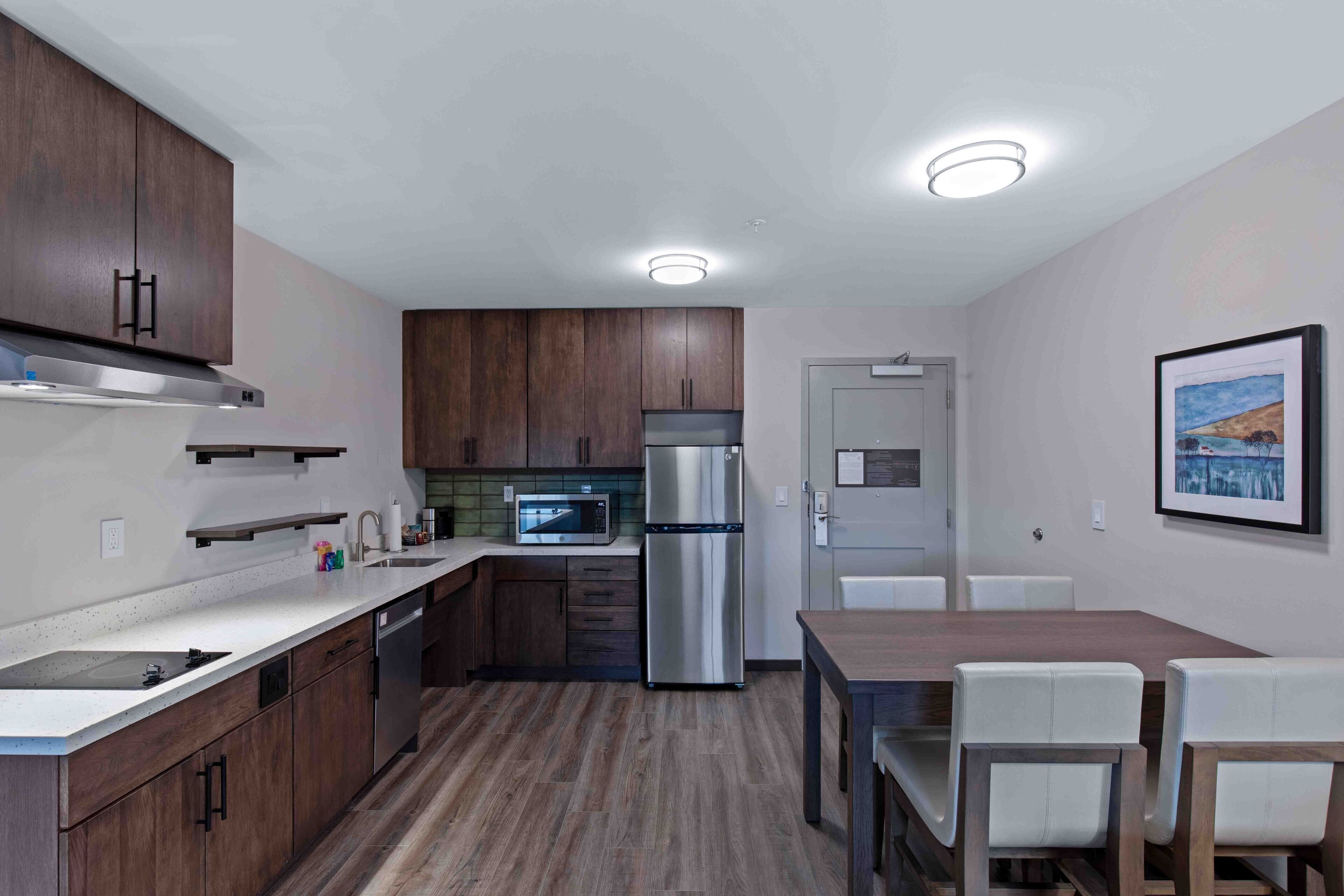 Eine moderne Küche mit Holzschränken, Edelstahlgeräten, einer Mikrowelle und einem Essbereich mit Tisch und Stühlen.