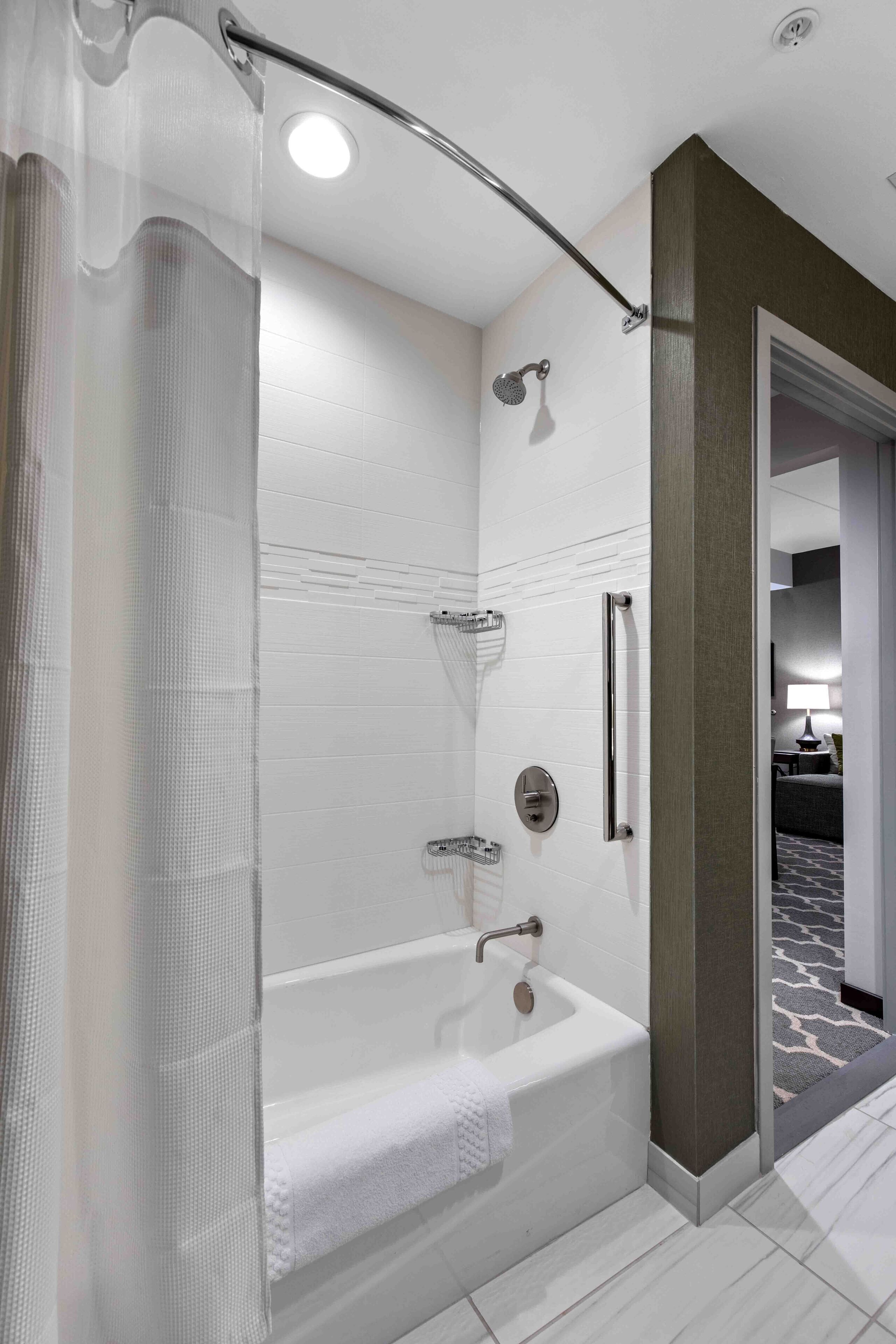 A modern bathroom with a bathtub, shower, and glass door.