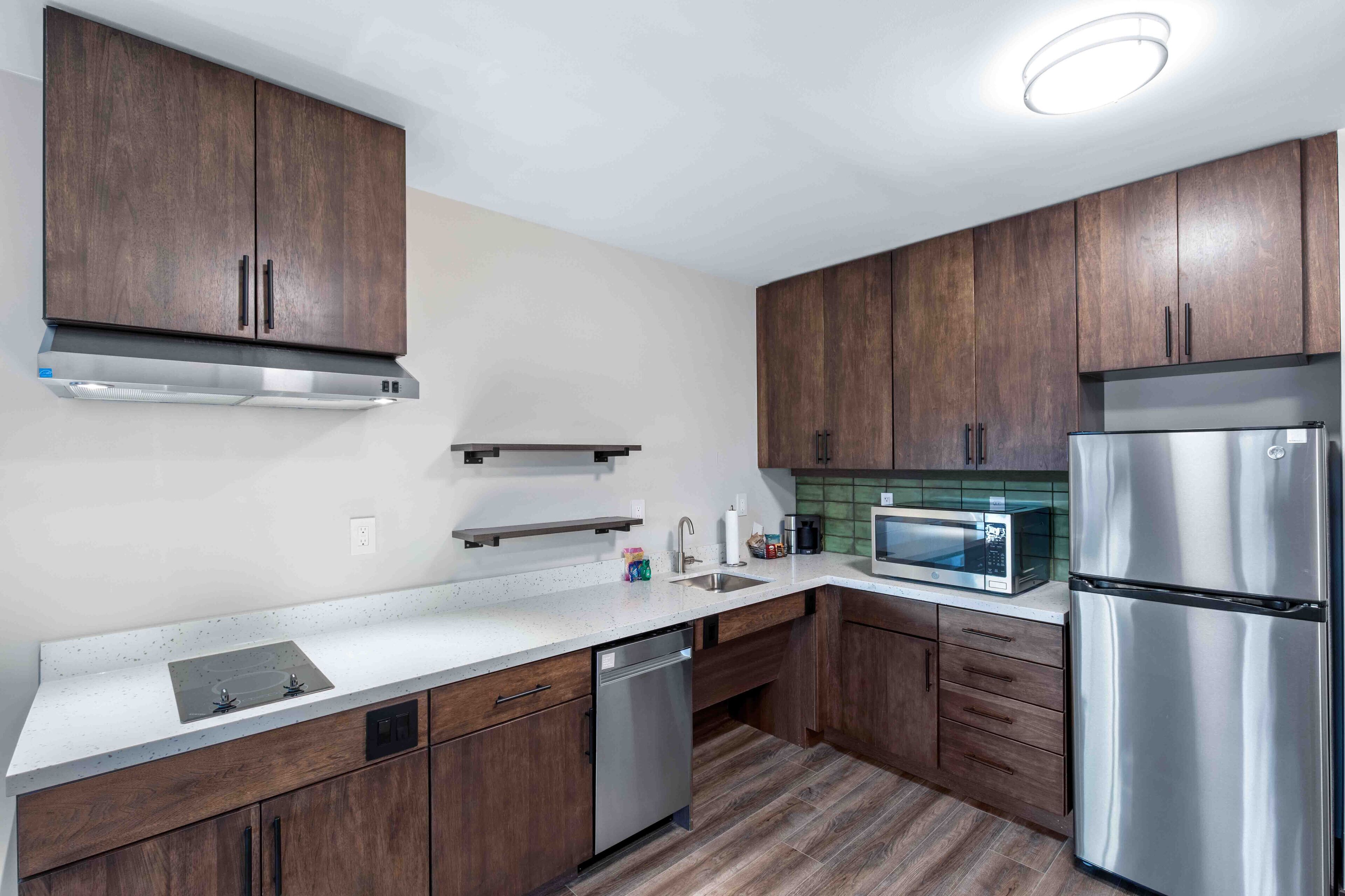 A modern kitchen with wooden cabinets, stainless steel appliances, and a white countertop.