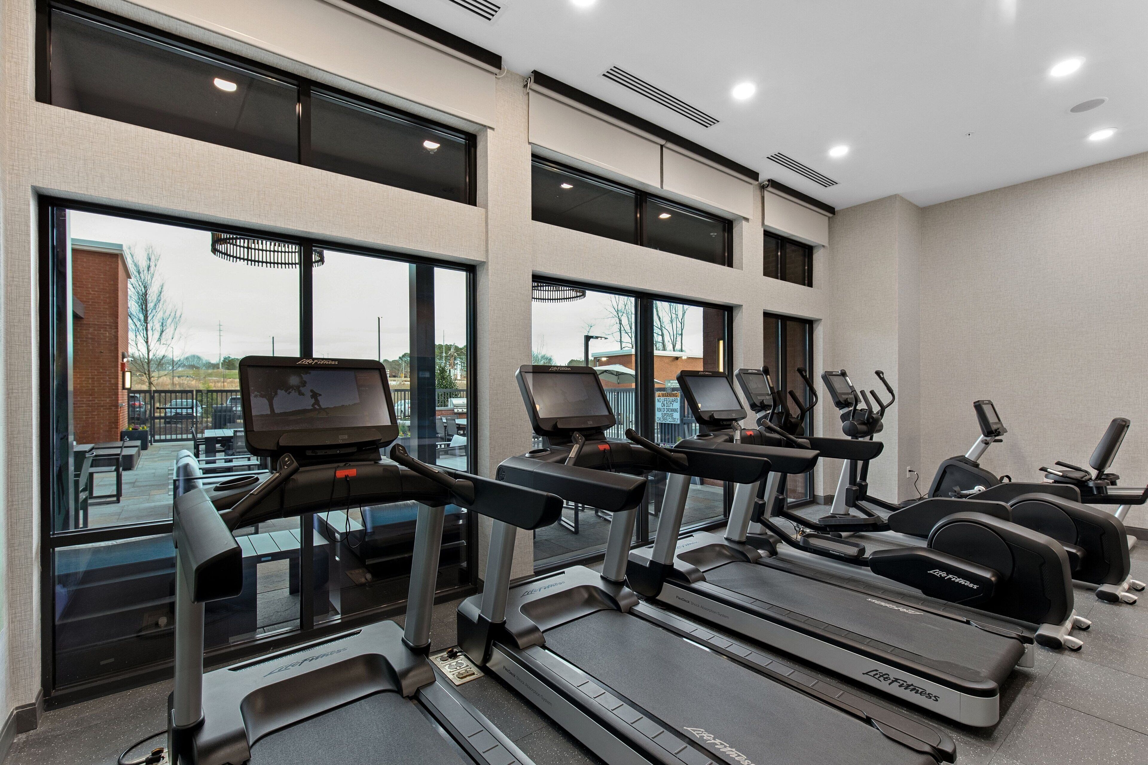 Une salle de sport équipée de tapis de course, de vélos elliptiques et de matériel de musculation.