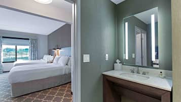Habitación de hotel con una cama grande, baño con espejo y vista a la ciudad.