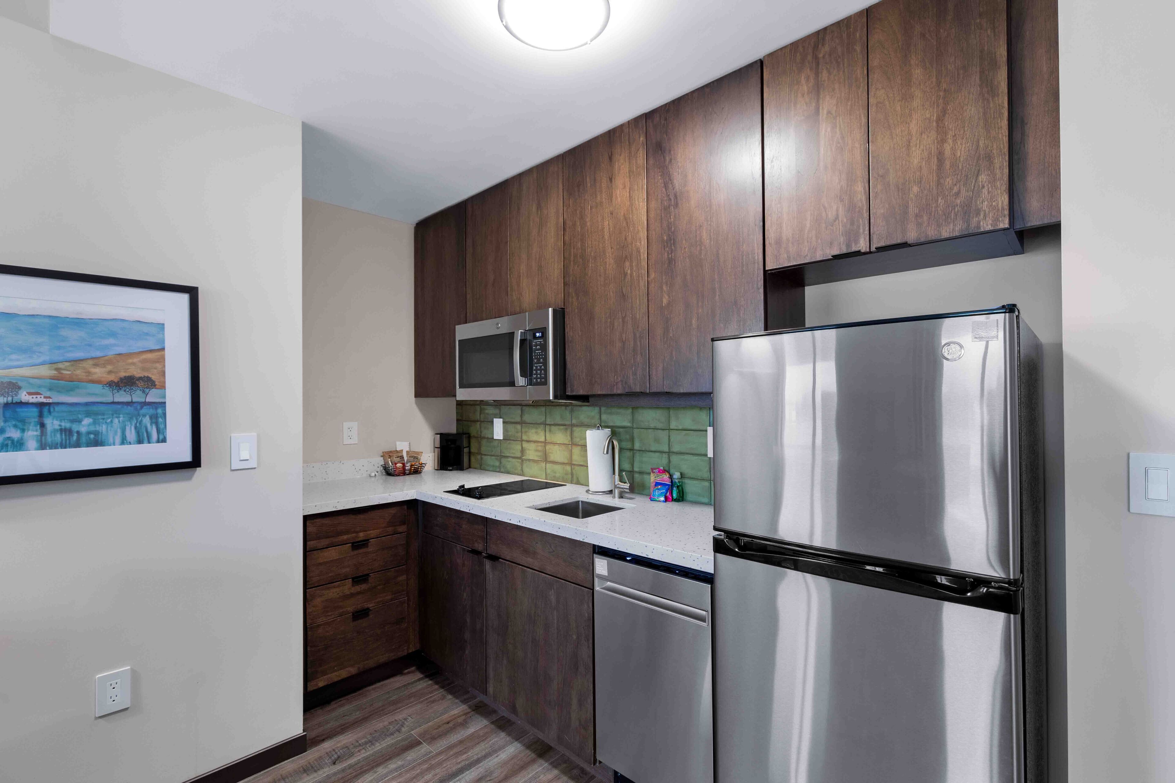 Una cocina moderna con armarios de madera oscura, electrodomésticos de acero inoxidable y salpicadero verde.