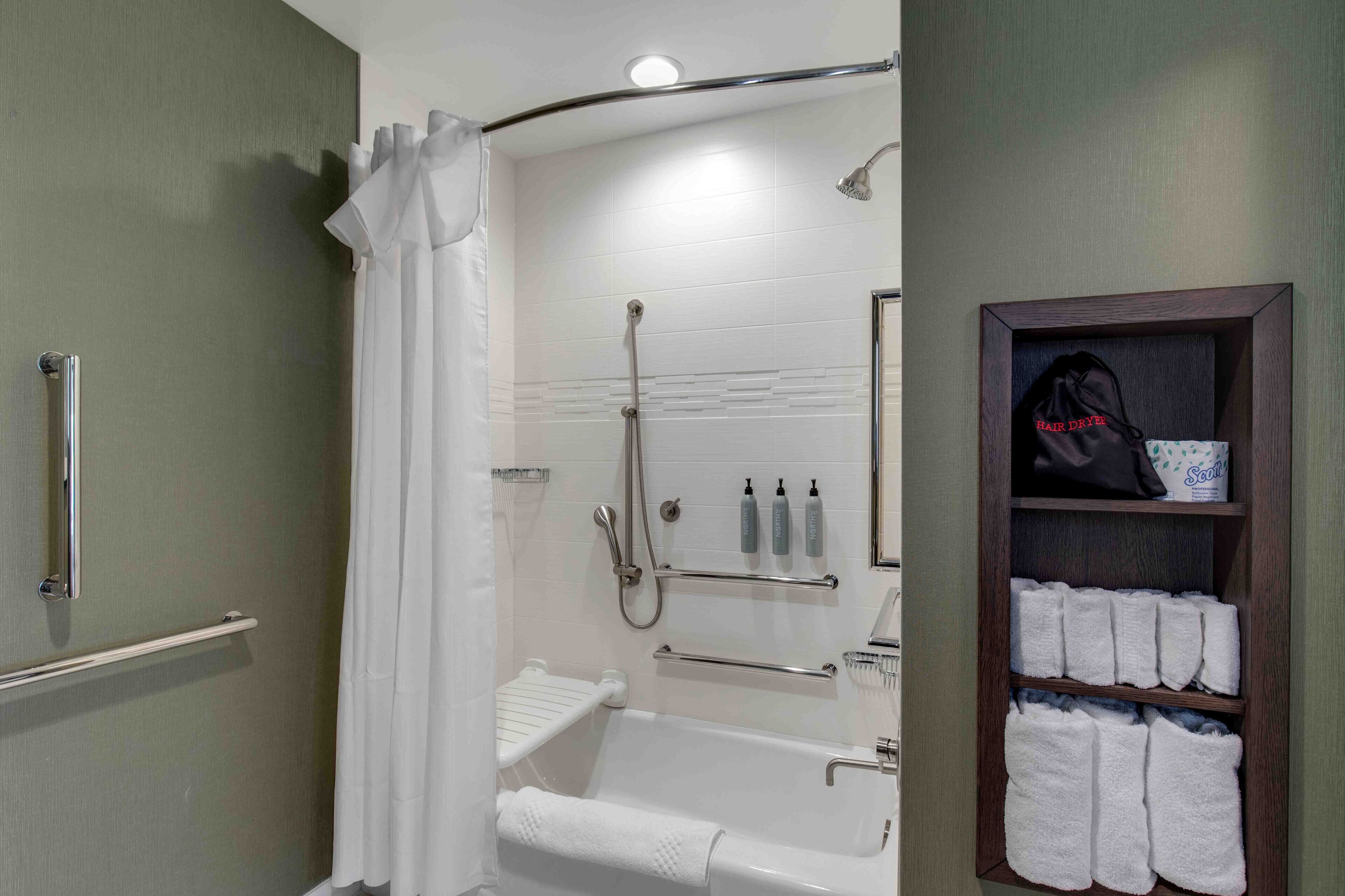 A bathroom with a bathtub, shower, and towel rack.
